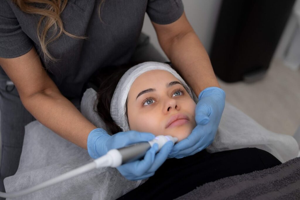 Hydrafacial treatment in progress at Skinoza Clinic — practitioner using a HydraFacial wand on a relaxed client during a multi-step facial cleanse and hydration session in London